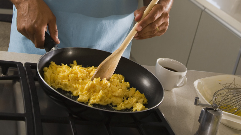 person stirring eggs with wooden spoon