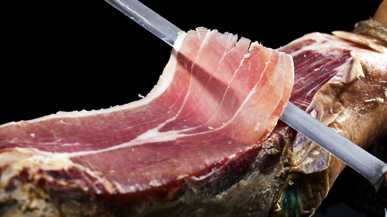 Prosciutto being sliced off whole leg