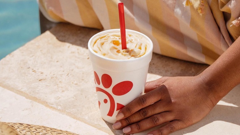 Person holding Chick-fil-A milkshake by pool