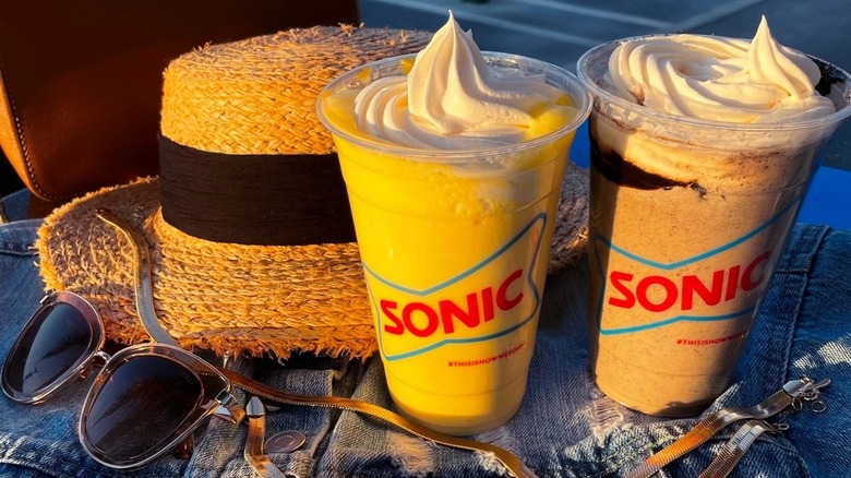 Two Sonic milkshakes next to hat and sunglasses