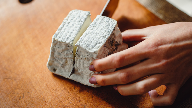 person slicing block of goat cheese