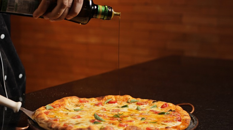 Drizzling olive oil on pizza