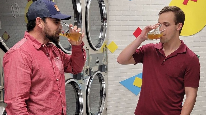 Men drinking beer in front of clothes washers