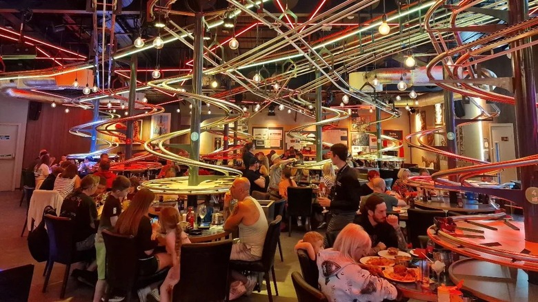 People eating under roller coaster tracks