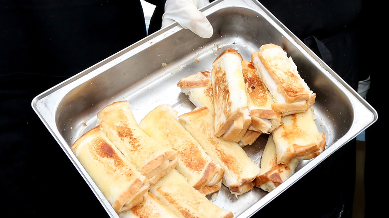 hand holding a tray of cheese rolls