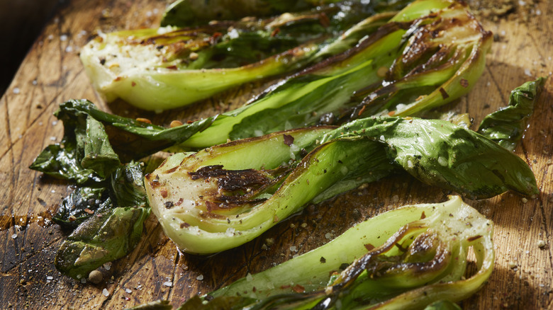 grilled bok choy on a wooden cutting board