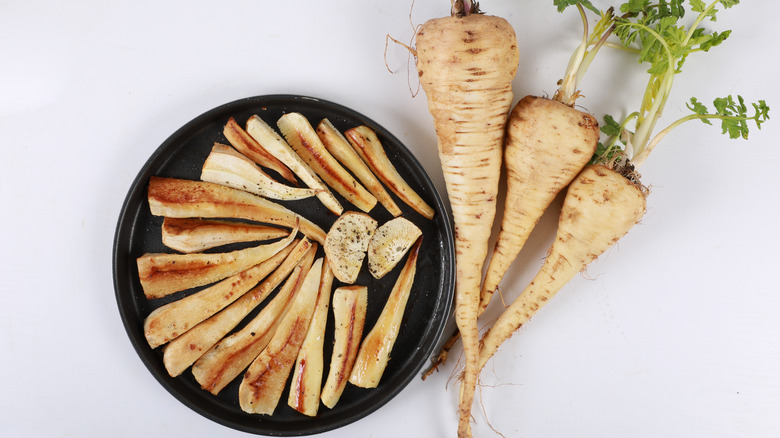 grilled parsnips on a black dish on white surface