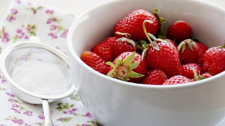 bowl of strawberries with flour sieve