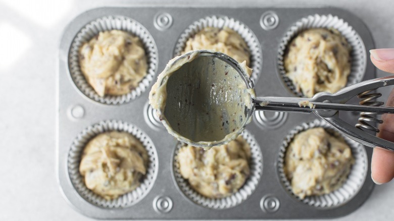 woman holding ice cream scoop above muffin tray