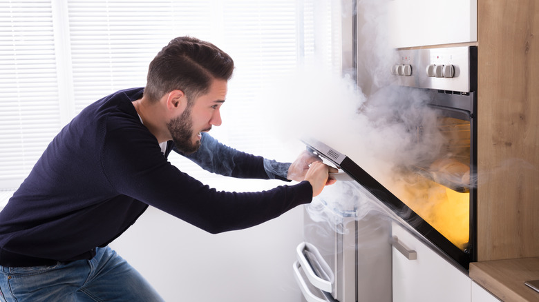 man opening smoking oven