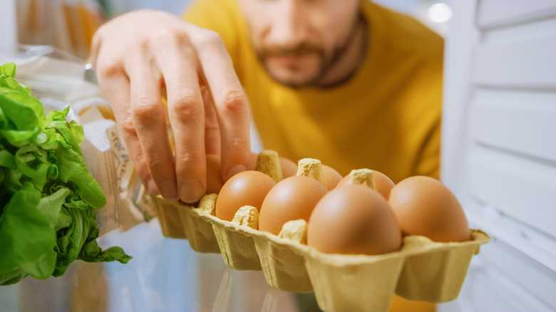 man taking eggs out of fridge