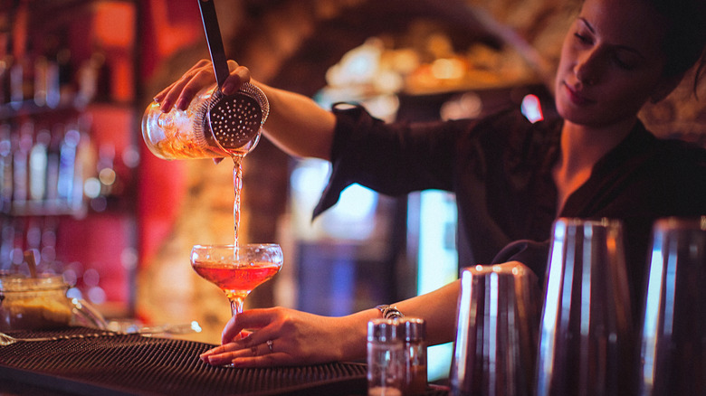 female bartender pouring cocktail 
