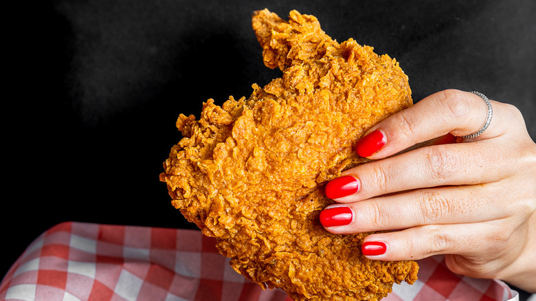 Hand holding piece of fried chicken