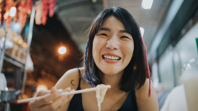 Thai woman eating noodles and smiling