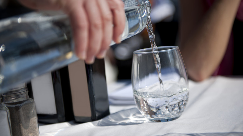 person pouring drinking water into glass