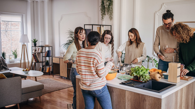 dinner party guests in kitchen drinking wine