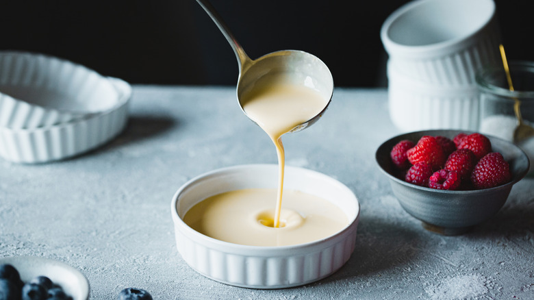 A ladle pouring custard into a ramekin