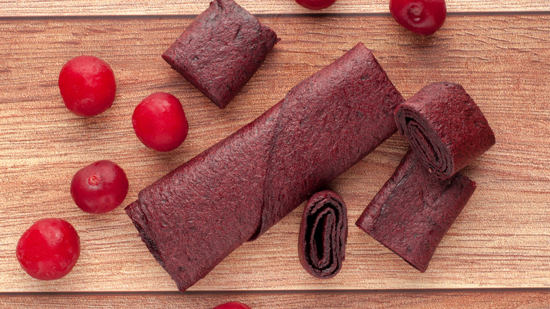 Rolled cherry fruit leather on wooden surface