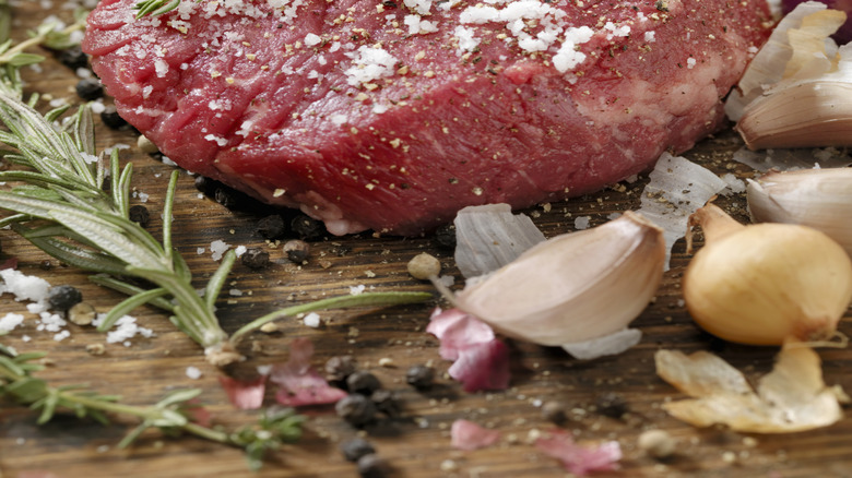 kosher salt on raw filet with fresh herbs, shallots, and garlic