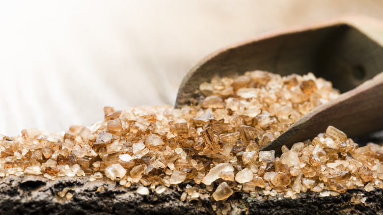 spoonful of smoked sea salt spills onto a rocky surface