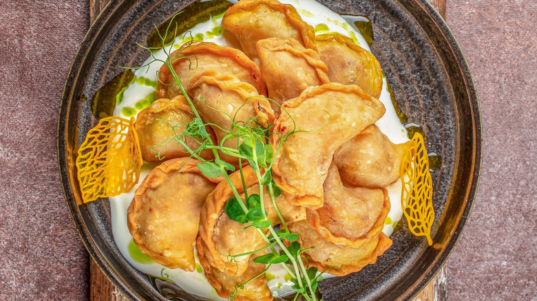 Crispy, golden pierogi on plate with garnishes.