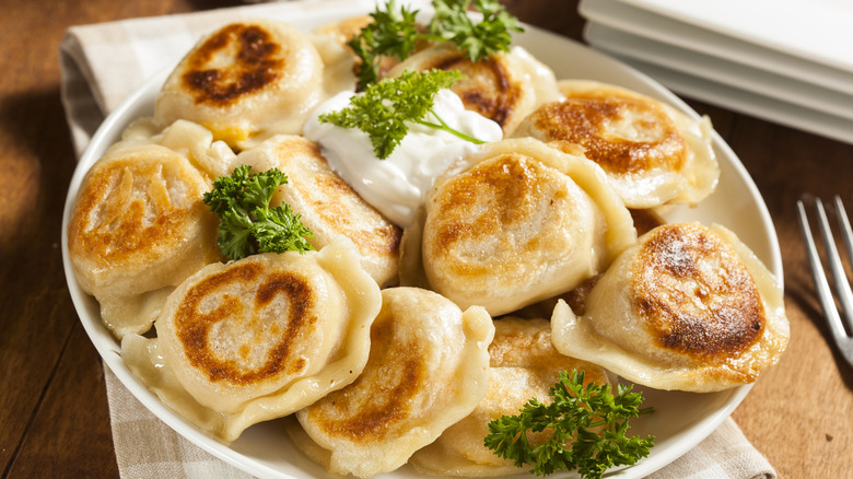 Plate of pierogi with parsley and sour cream.