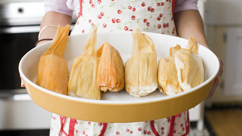 holding large tray of tamales