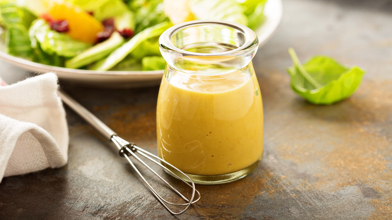 Jar of vinaigrette with salad in background