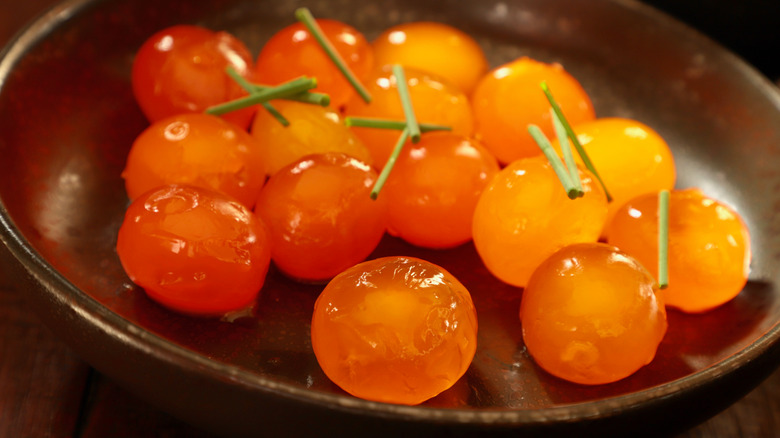 orange cured egg yolks in a dark dish with green garnish