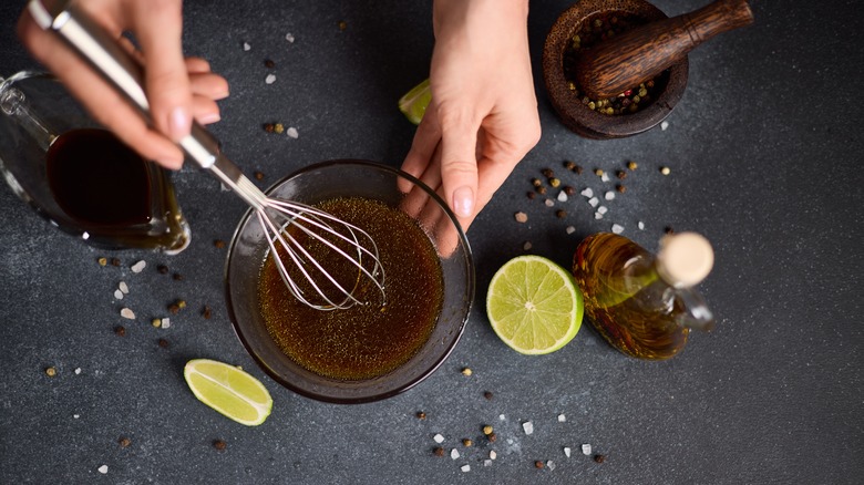 Person mixing teriyaki sauce on a dark gray background