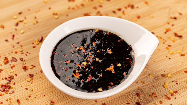 A bowl of teriyaki sauce with red pepper flakes on top