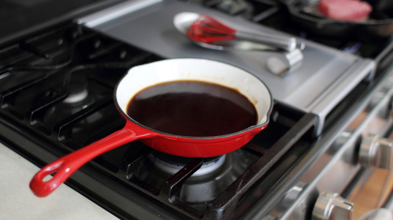 Reducing sauce on a stove in a red sauce pan