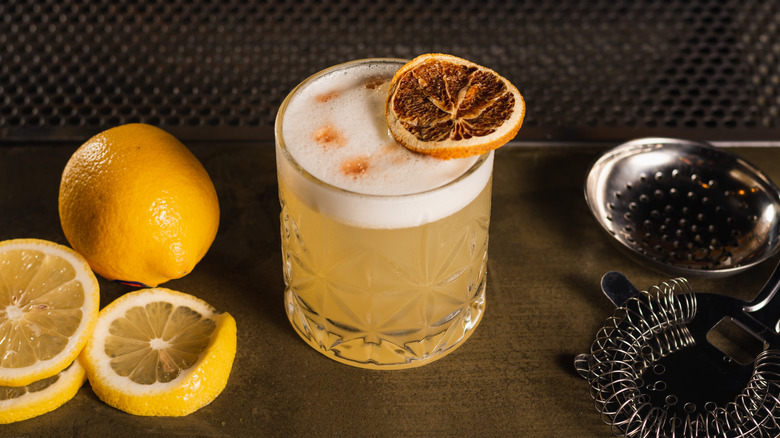 whiskey sour topped with scorched lemon slices and orange bitters