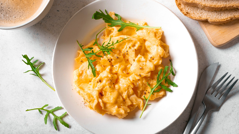 Scrambled eggs in a white dish with knife and fork