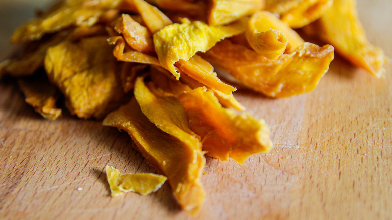 Dried mangoes on a wooden board.