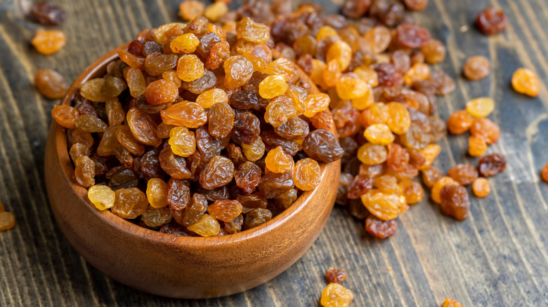 A wooden bowl of golden raisins.