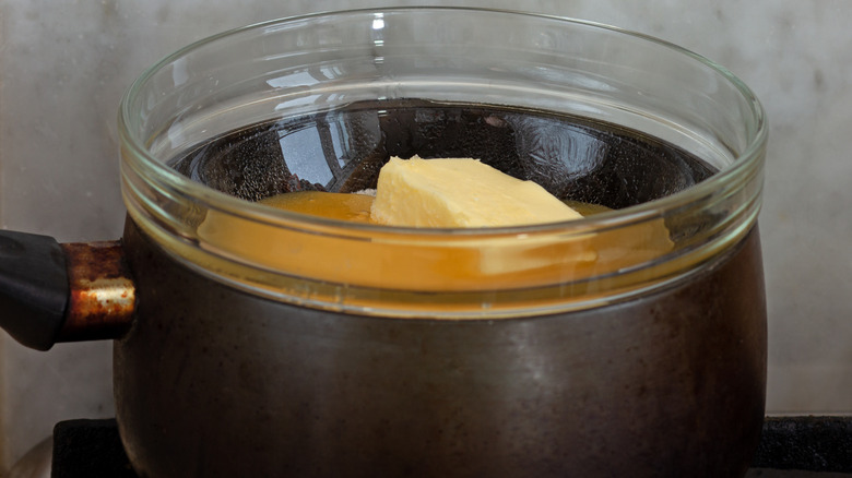 Butter melting double-boiler style in a glass dish set inside a stovetop pot