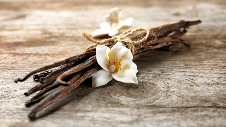 Vanilla pods and flower tied with string on wooden table