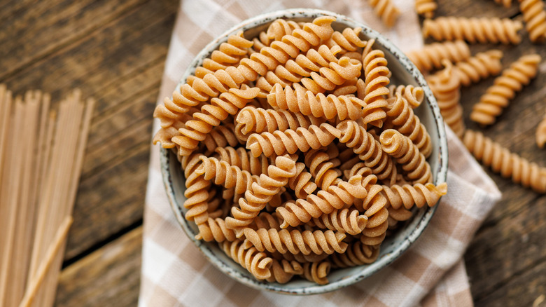 Uncooked pasta in a bowl on a checkered kitchen cloth