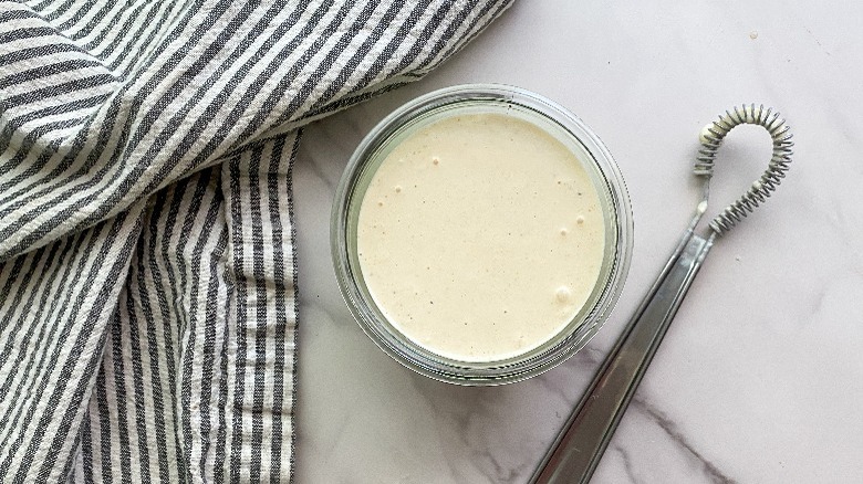 glass jar with sauce inside and whisk