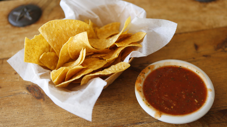 Red salsa and tortilla chips on wooden restaurant table