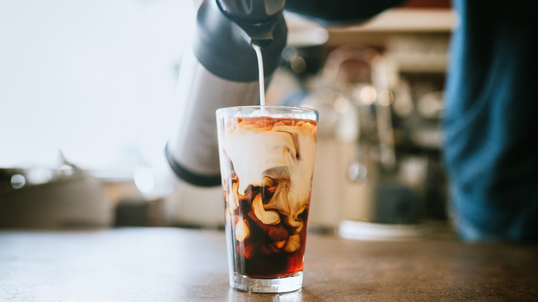 Adding milk to a glass of cold brew