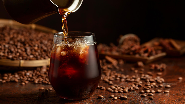 A glass of cold brew coffee with coffee beans