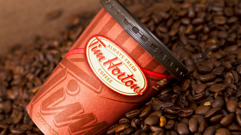 Tim Hortons coffee cup resting on coffee beans