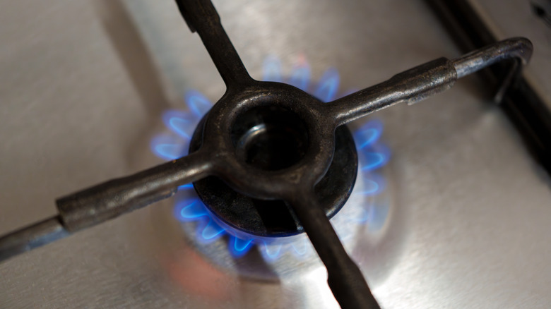 A gas burner is on, revealing cool blue flames