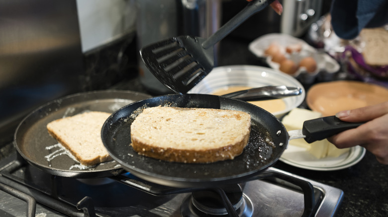 person toasting one side of sandwich bread