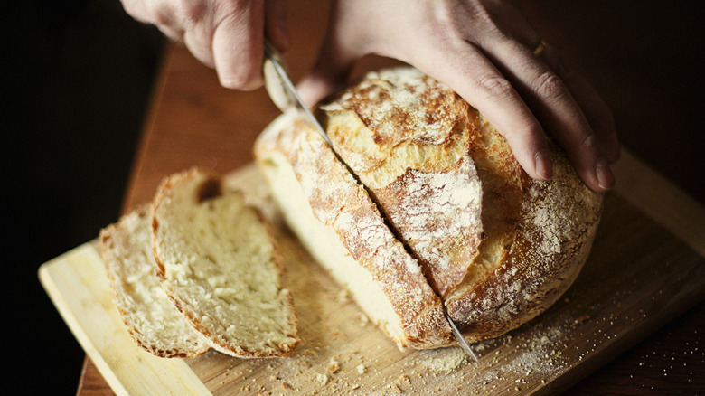 person slicing a loaf of freshly baked bread