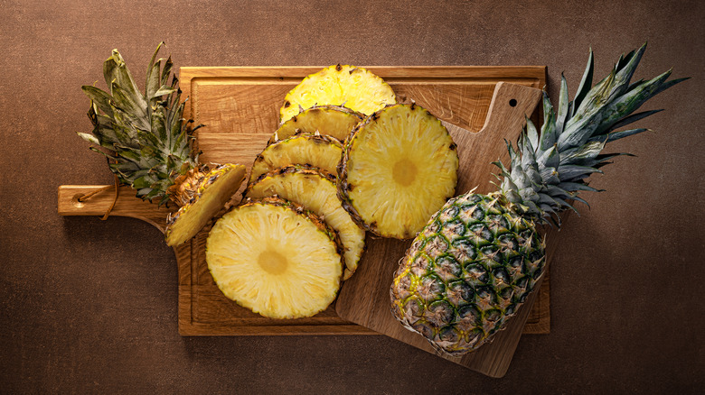 sliced and whole pineapple on a cutting board