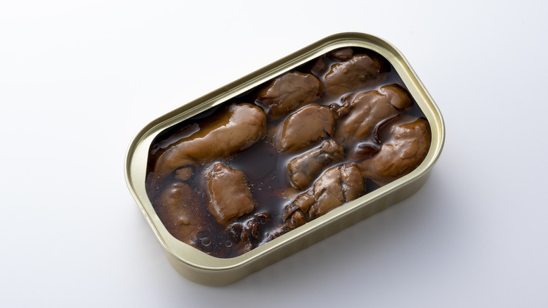 Canned oysters in oil on blank white surface