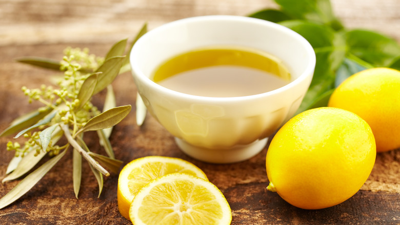 Bowl of olive oil with lemons on the side.